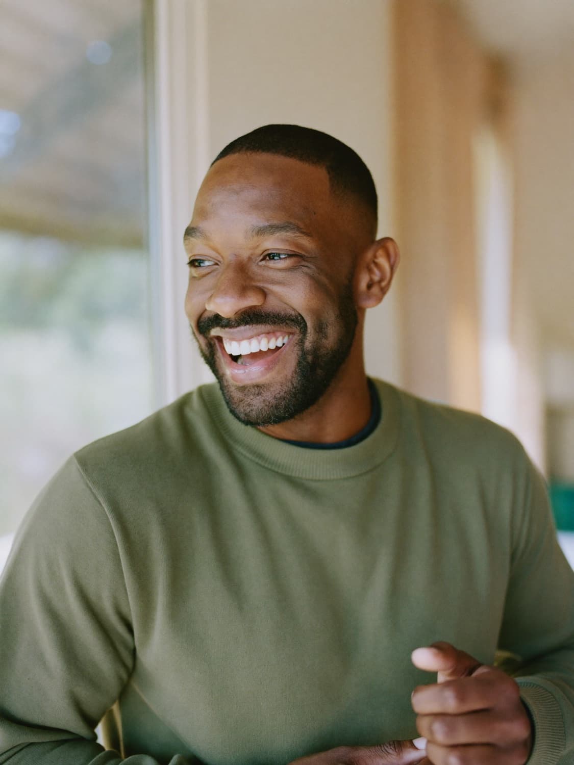 A man laughing at home by a window