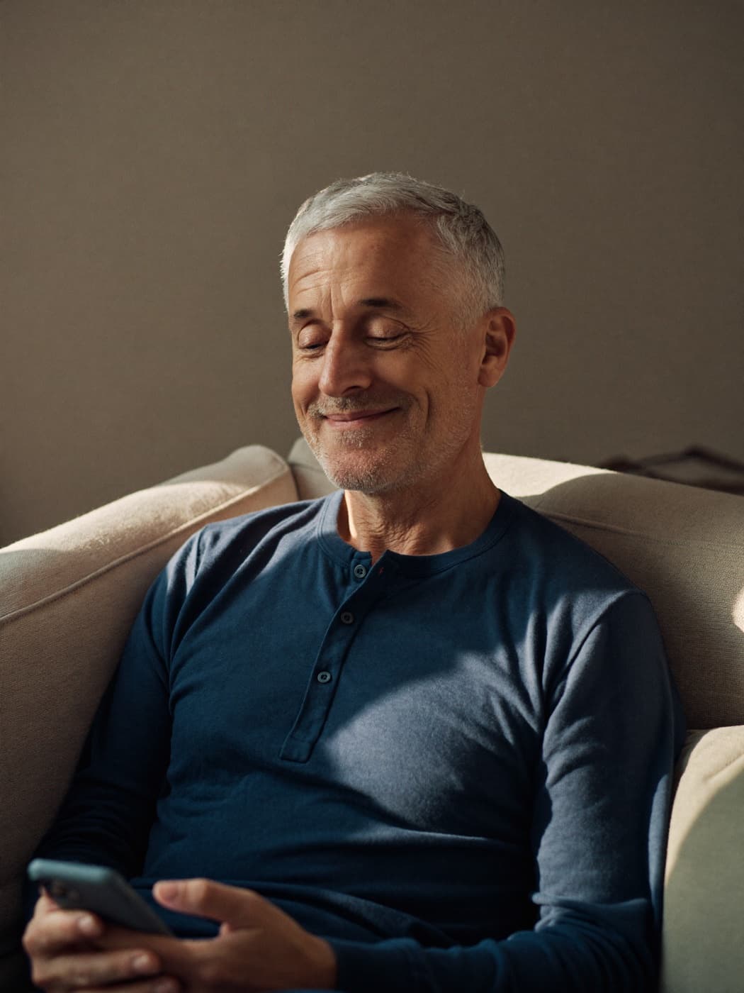 A man relaxing on his sofa, looking at his phone